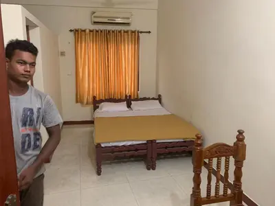 a man standing in front of a bed in a room at Jinan city centre in Alwaye