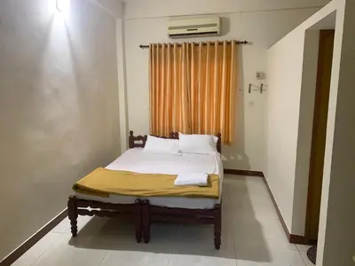 a bedroom with a bed with a yellow blanket on it at Jinan city centre in Alwaye