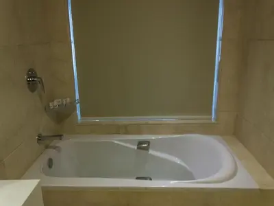 a bath tub in a bathroom with a mirror at Diana Heights Luxury Hotel in Nedumbassery