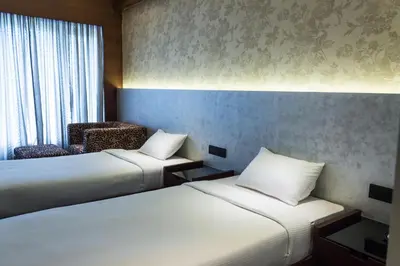 a hotel room with two beds and a chair at Diana Heights Luxury Hotel in Nedumbassery