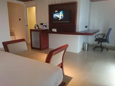a room with a table and chairs and a tv at Diana Heights Luxury Hotel in Nedumbassery