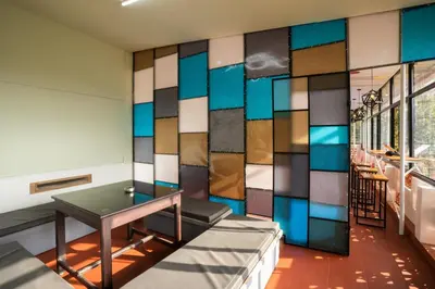 a room with a table and a wall of stained glass at Zostel Coorg, Madikeri in Madikeri