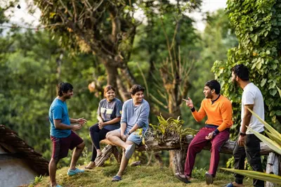 a group of people sitting on a bench in the grass at Zostel Coorg, Madikeri in Madikeri