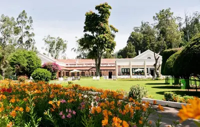 a garden with flowers in front of a building at Savoy - IHCL SeleQtions in Ooty