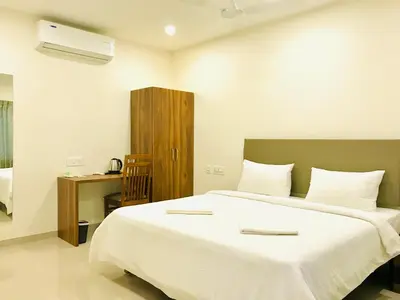 a bedroom with a large white bed and a desk at MALLI resort in Dhārāpuram