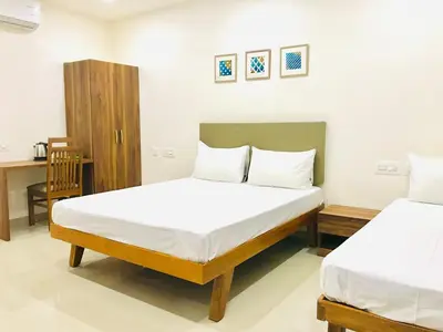 a bedroom with two beds and a chair in it at MALLI resort in Dhārāpuram