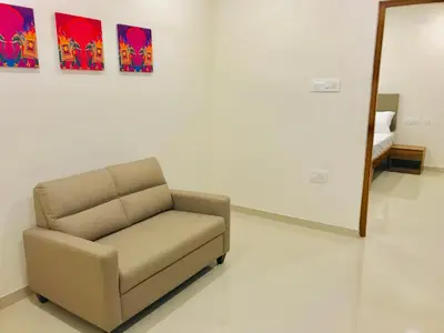 a chair in a room with paintings on the wall at MALLI resort in Dhārāpuram