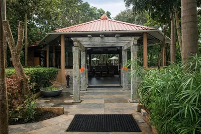 a pavilion with a table and chairs in a garden at Regenta Jungle Resort Kabini Springs in Begūr