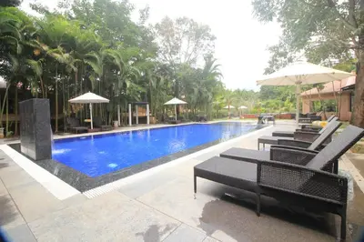 a large swimming pool with chairs and umbrellas at Regenta Jungle Resort Kabini Springs in Begūr