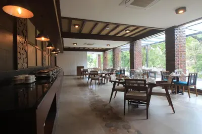 a dining room with tables and chairs and windows at Regenta Jungle Resort Kabini Springs in Begūr