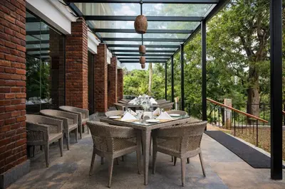 a dining area with a table and chairs on a patio at Regenta Jungle Resort Kabini Springs in Begūr
