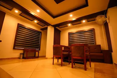 a dining room with a table and chairs and a couch at Zubis Inn Hotel in Kalpetta