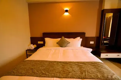 a bedroom with a large bed with white pillows at Zubis Inn Hotel in Kalpetta