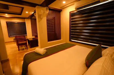 a bedroom with a bed and a window with a chair at Zubis Inn Hotel in Kalpetta