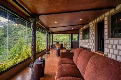 a living room with a couch and large windows at The Berg Ooty Queen of Hills in Ooty