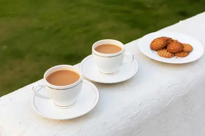 two cups of coffee and a plate of cookies on a table at The Berg Ooty Queen of Hills in Ooty