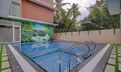 a swimming pool in front of a house with a mural at Treebo Golden Terminal Kochi Airport With Swimming Pool in Cochin