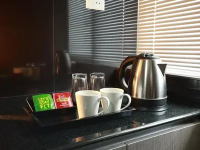a tray with cups and coffee mugs on a counter at Transit Suites by GrandWest in Nedumbassery