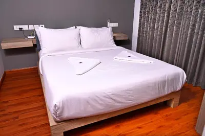 a bed with white sheets and white pillows at Transit Suites by GrandWest in Nedumbassery