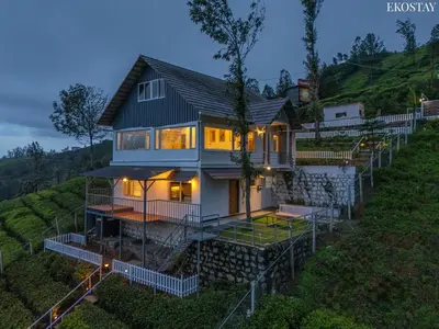 a house on a hill with its lights on at EKO STAY - Woodside Ivy in Ooty
