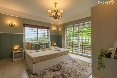 a bedroom with a bed with a chandelier and windows at EKO STAY - Woodside Ivy in Ooty