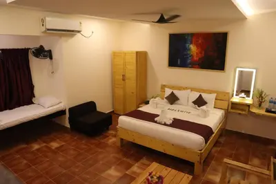 a bedroom with a bed and a chair in it at Royal Destiny Resort in Malaiyāndipattanam