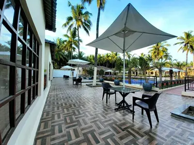 a patio with a table and chairs and an umbrella at Royal Destiny Resort in Malaiyāndipattanam