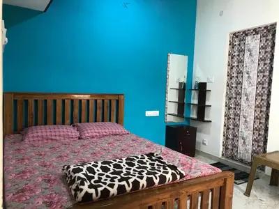 a bedroom with a bed with a blue wall at Kodai Countryside Homestay in Kodaikānāl