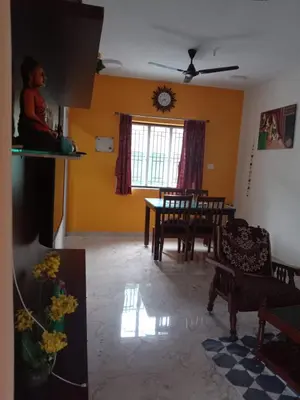 a living room with yellow walls and a table and chairs at Kodai Countryside Homestay in Kodaikānāl