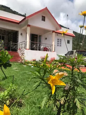 a house with a yellow flower in the yard at Kodai Countryside Homestay in Kodaikānāl