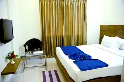 a bedroom with a bed and a chair and a television at Vismaya Comforts in Mysore