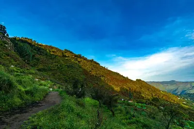 a dirt road on a hill with a blue sky at Warmth Hill Crest in Kodaikānāl