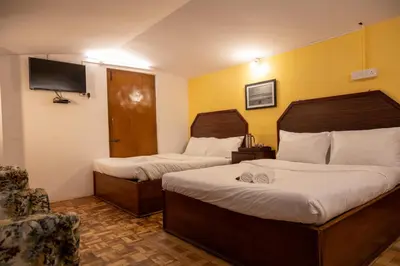 a hotel room with two beds and a tv at Aakash Rooms and Cottages, in Ooty