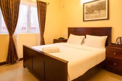 a bedroom with a large bed and a window at Aakash Rooms and Cottages, in Ooty
