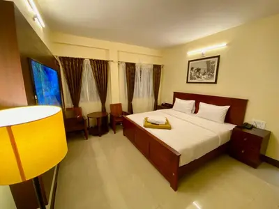 a bedroom with a large bed and a yellow lamp at Aakash Rooms and Cottages, in Ooty