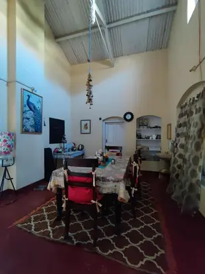 a living room with a table and chairs on a rug at Zeus Bungalow in Kotagiri