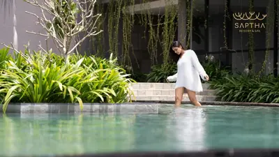 a woman in a white dress walking in a pool of water at Saptha Resort and Spa in Sultan Bathery