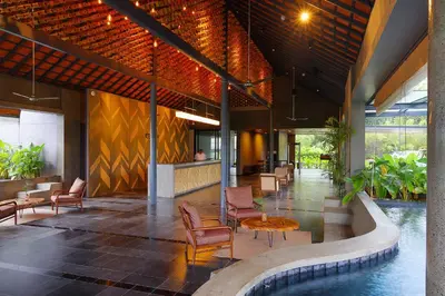 a lobby of a hotel with a pool and chairs at Saptha Resort and Spa in Sultan Bathery