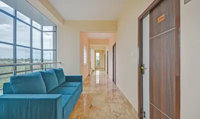 a living room with a blue couch and a balcony at Treebo Everest Residency Tidel Park, 15 Mins From Coimbatore International Airport in Coimbatore
