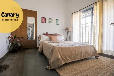 a bedroom with a bed and a large window at Rendezvous in Coonoor
