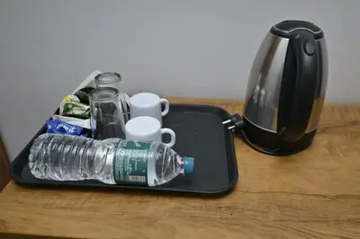 a bottle of water in a tray next to a coffee pot at Nirupama,Hotel Aluva 700 Mtr From Aluva Railway Station in Alwaye