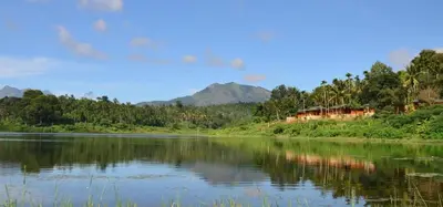 a view of a river with houses and trees at LakeRose Wayanad Resort - Water Front Grandeur in Kalpetta