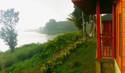 a red building with a view of a river at LakeRose Wayanad Resort - Water Front Grandeur in Kalpetta