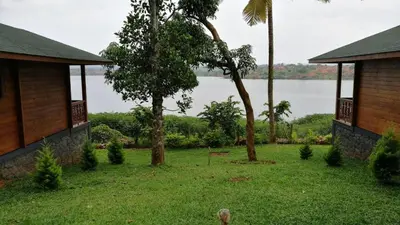a yard with two houses and a view of the water at LakeRose Wayanad Resort - Water Front Grandeur in Kalpetta