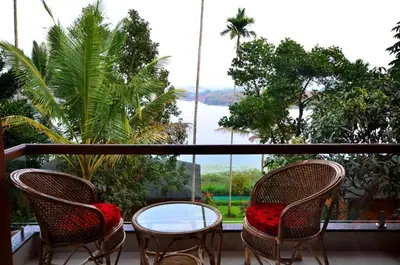 a balcony with two chairs and a glass table at LakeRose Wayanad Resort - Superior lake view in Kalpetta