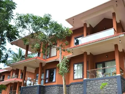 an orange building with trees in front of it at LakeRose Wayanad Resort - Superior lake view in Kalpetta
