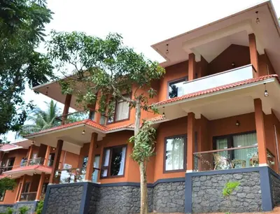 an orange building with a tree in front of it at LakeRose Wayanad Resort - Superior lake view in Kalpetta