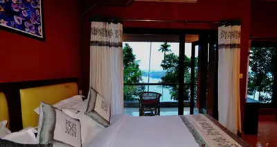 a bedroom with a bed and a large window at LakeRose Wayanad Resort - Lake view in Kalpetta