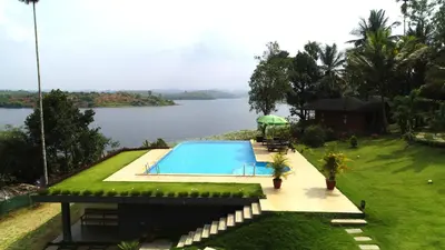 a swimming pool next to a body of water at LakeRose Wayanad Resort - Lake view in Kalpetta