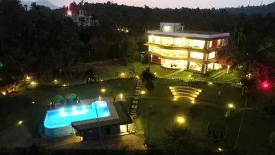 a large building with a swimming pool in front of it at LakeRose Wayanad Resort - Lake view in Kalpetta